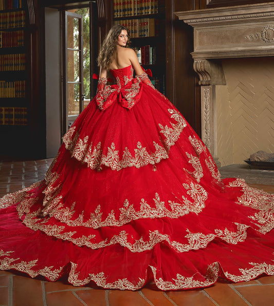 Red ball gown with gold embroidery in a room with books and a fireplace.