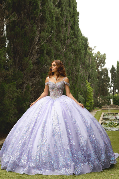 Woman in a purple embroidered gown standing in a garden with trees and grass.