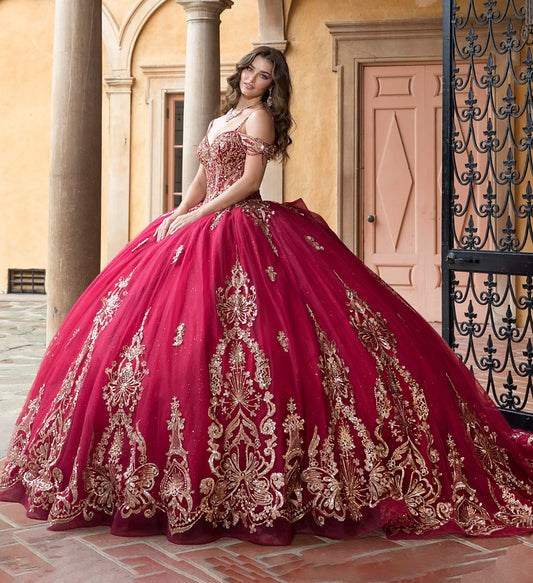 Woman in a red and gold embroidered gown standing in front of a building with columns.