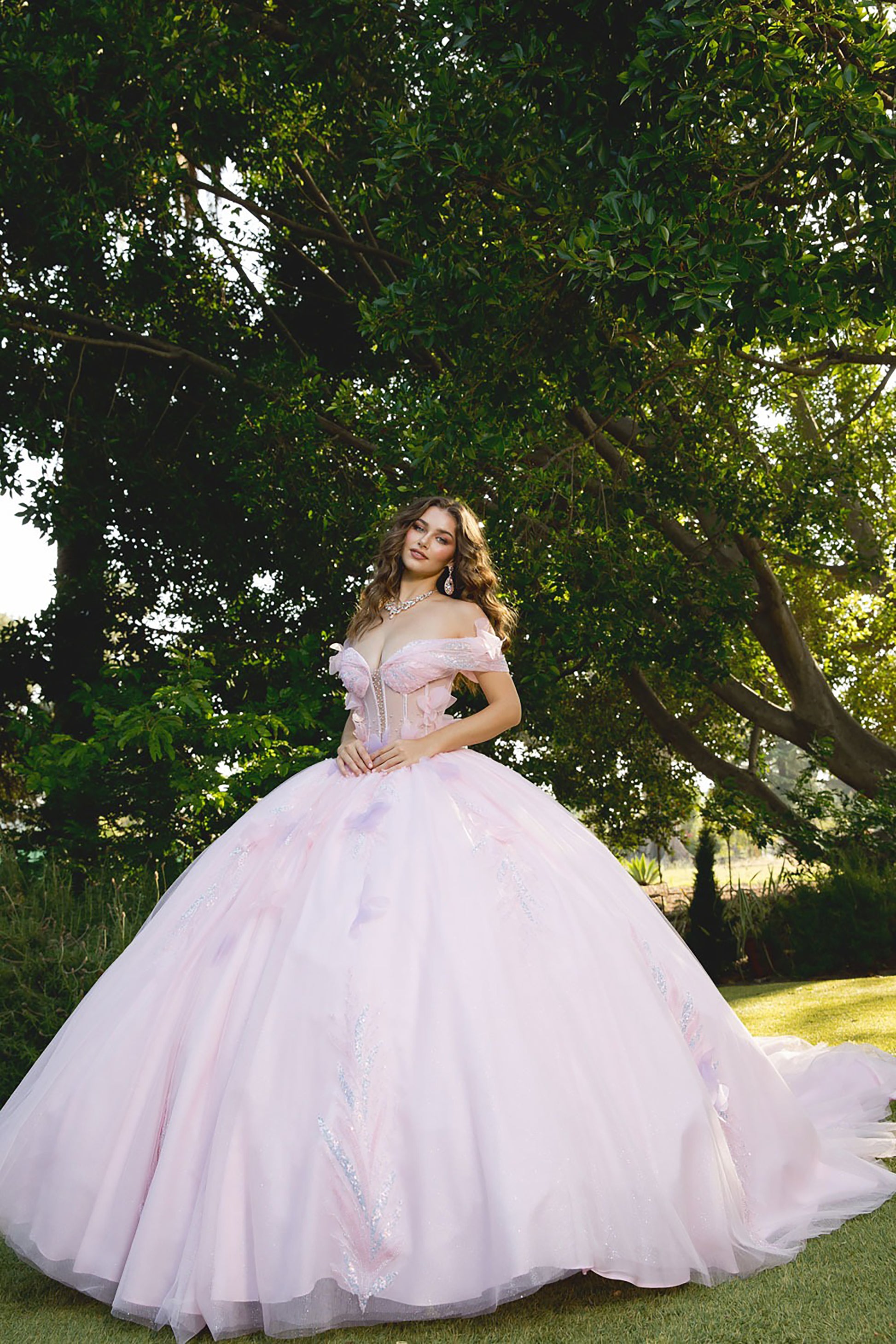 Woman in a pink wedding dress standing outdoors with trees in the background