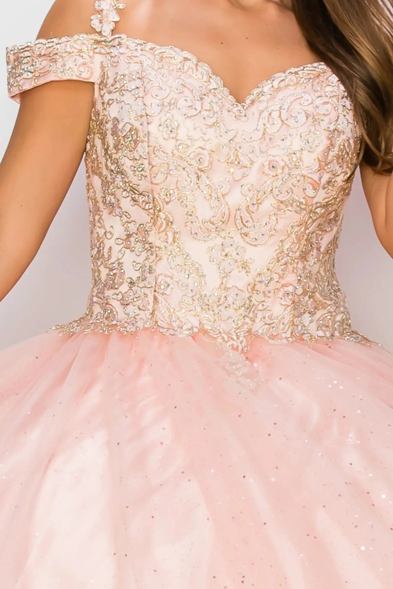 Close-up of a pink and gold off-shoulder dress with intricate detailing.