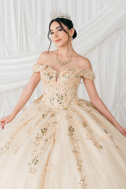 Woman in a beige ball gown with gold embellishments against a white background