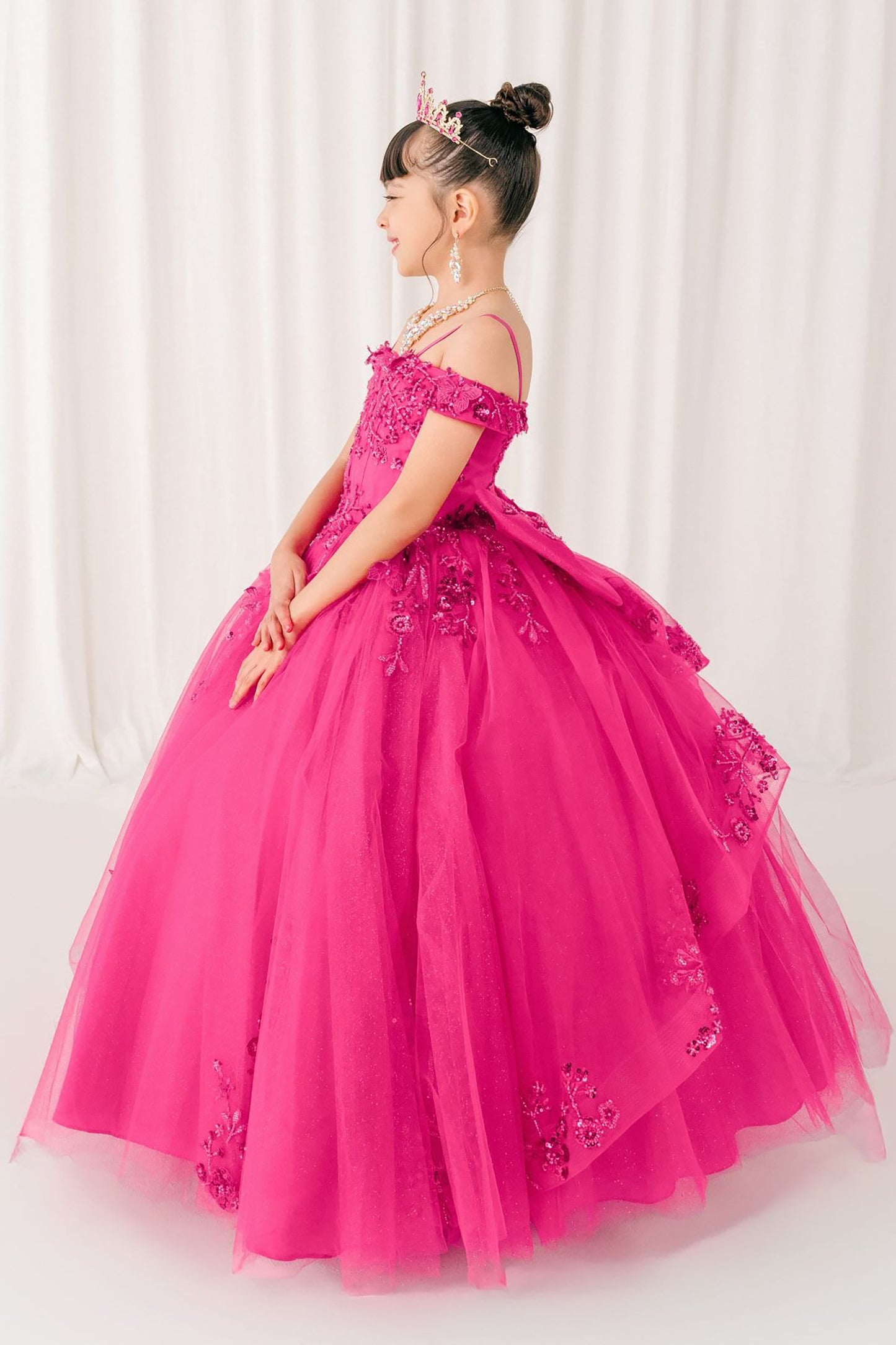 kid in a fuchsia formal mini quince gown with floral details against a white curtain background