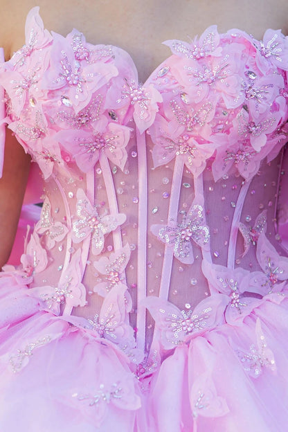 Close-up of a pink quinceanera dress with florals and butterflies and bow details