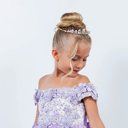 Young girl in a purple dress with floral details and a pearl tiara on a light gray background