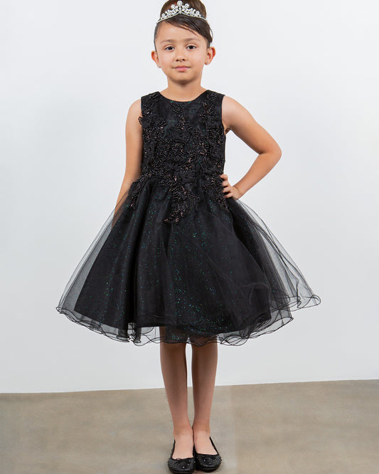 Young girl wearing a black dress with a tiara against a plain background