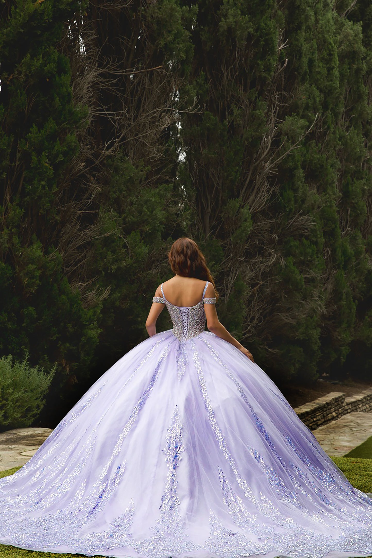 Woman in a white wedding dress standing in a garden with trees in the background