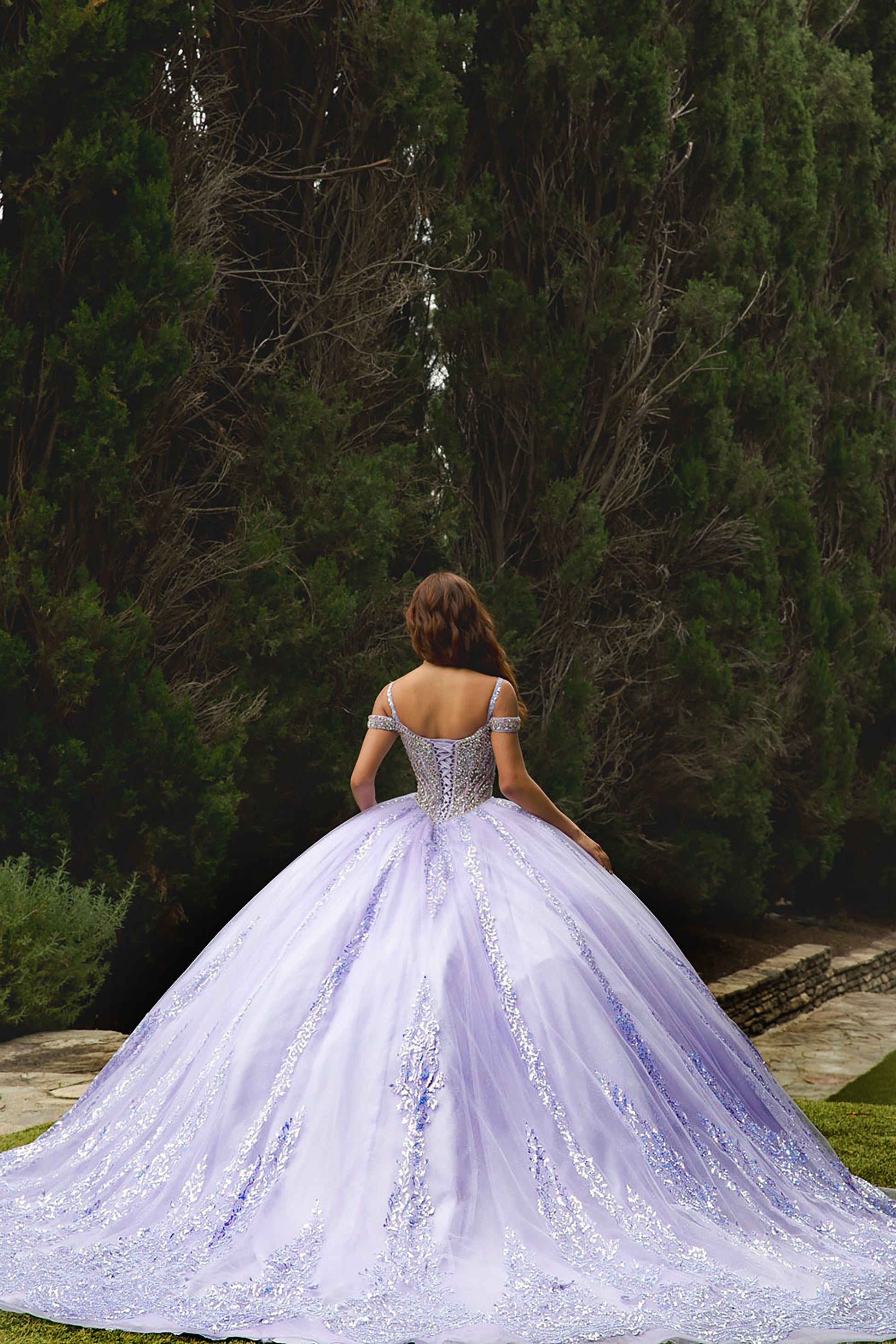 Woman in a white wedding dress standing in a garden with trees in the background