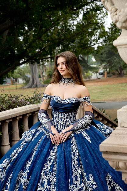 Woman in a blue and white embroidered gown standing outdoors.