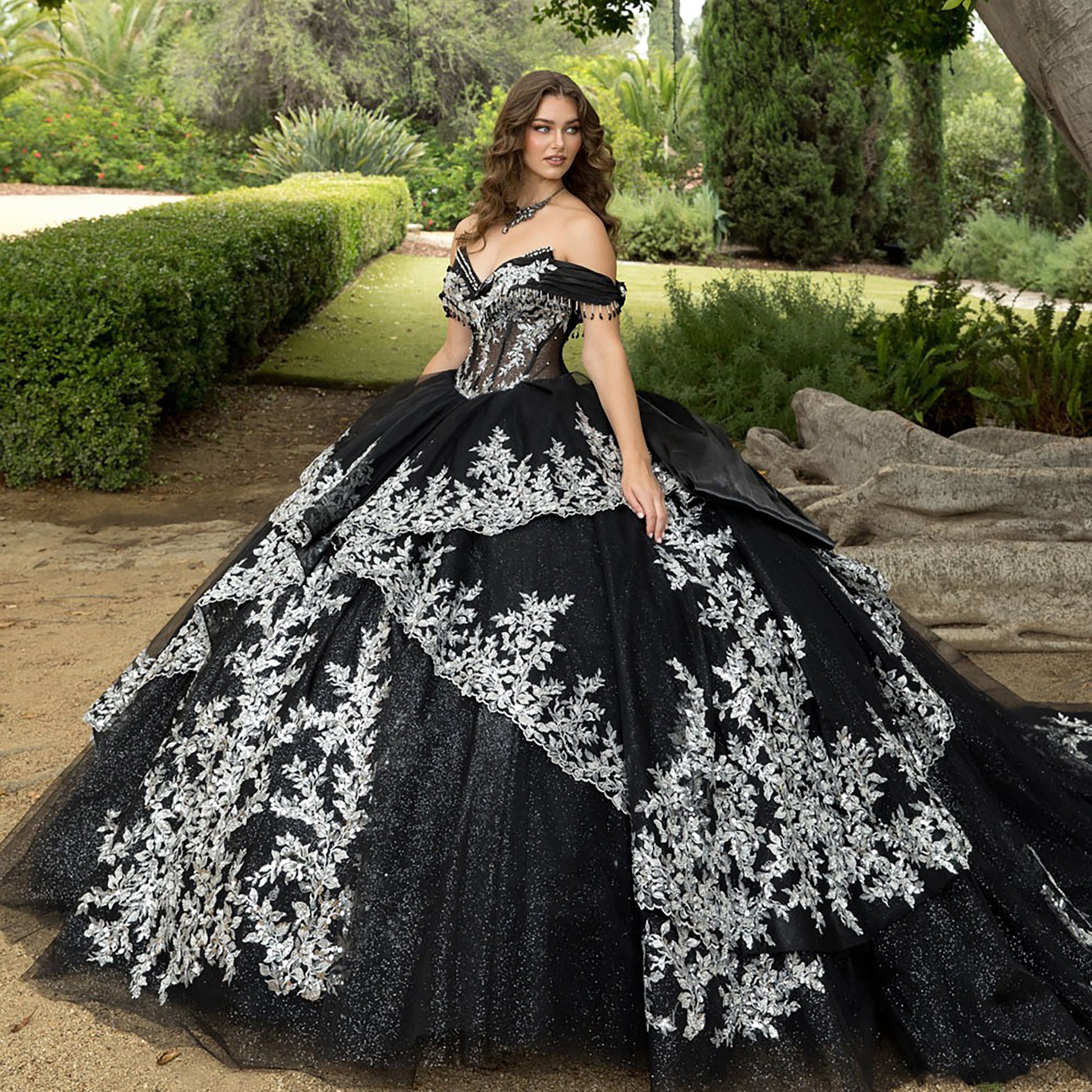 Woman in a black and white ball gown standing in a garden.