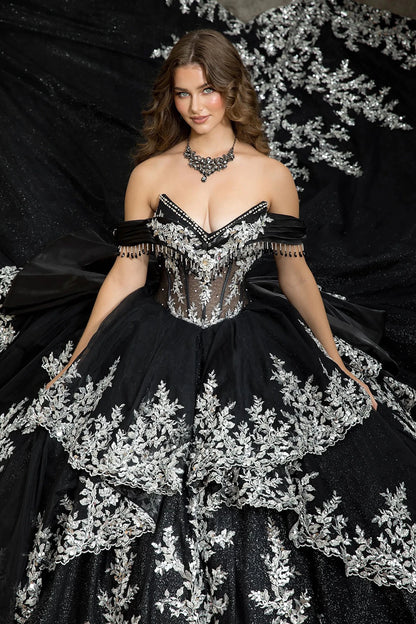 Woman in a v neck black and silver embroidery ball gown standing in front of a large tree