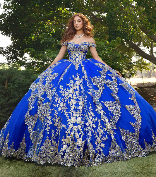 Woman wearing a blue and silver ball gown with floral patterns outdoors.
