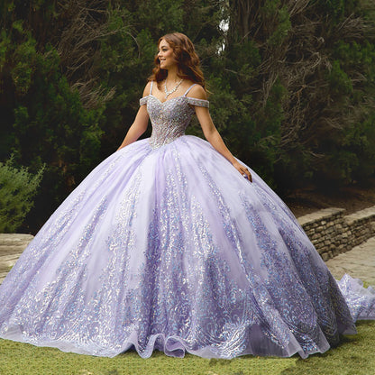 Woman in a sparkling purple gown standing outdoors with greenery in the background