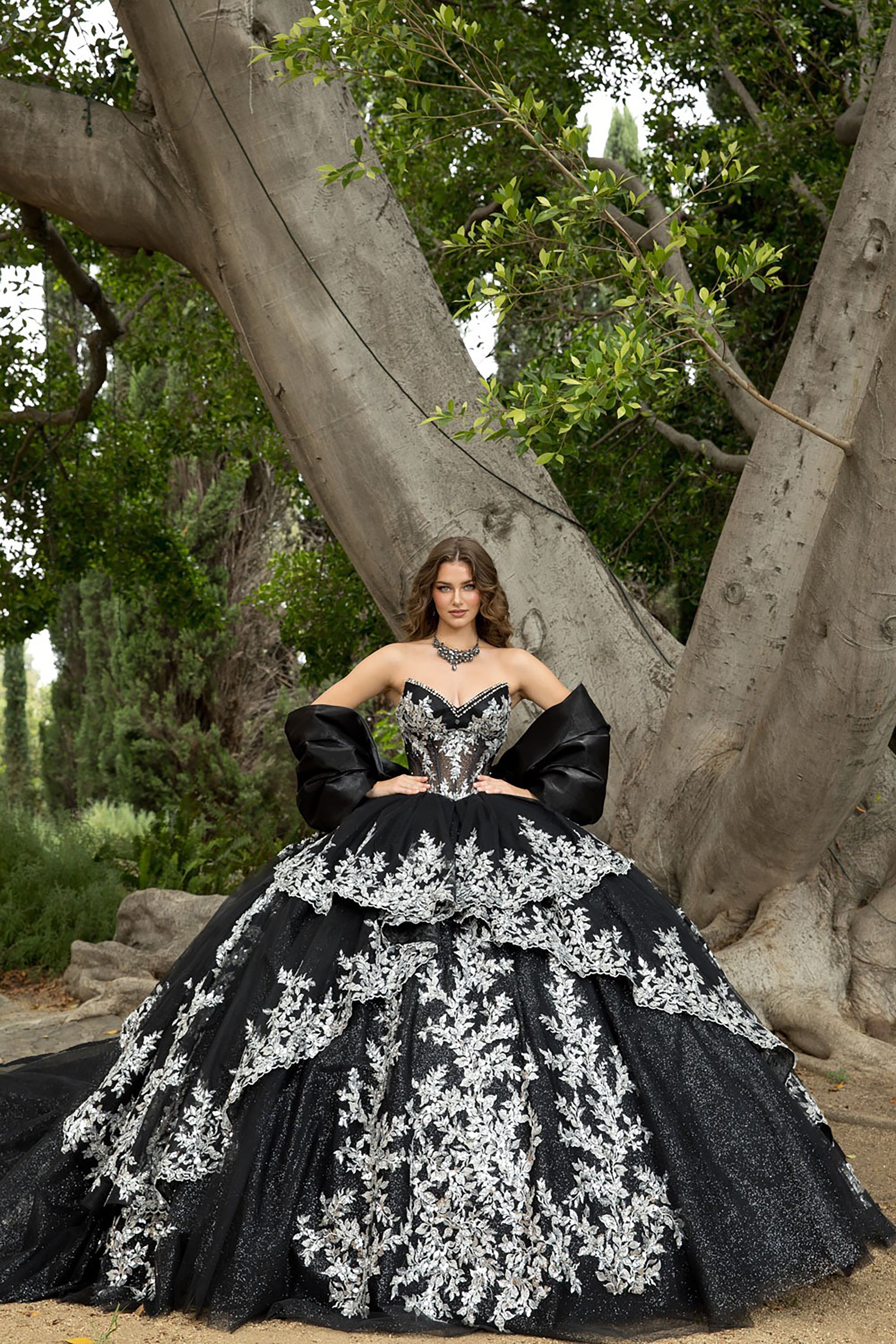 Woman in a black and white gown standing in front of a large tree