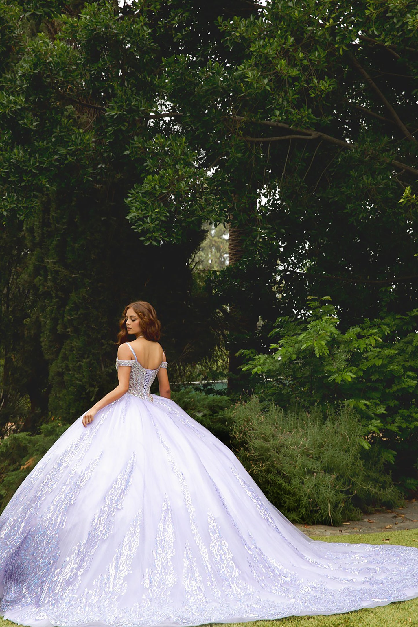 Woman in a white wedding dress standing in a lush green garden.