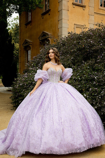 Woman in a lavender gown standing in front of a building with greenery