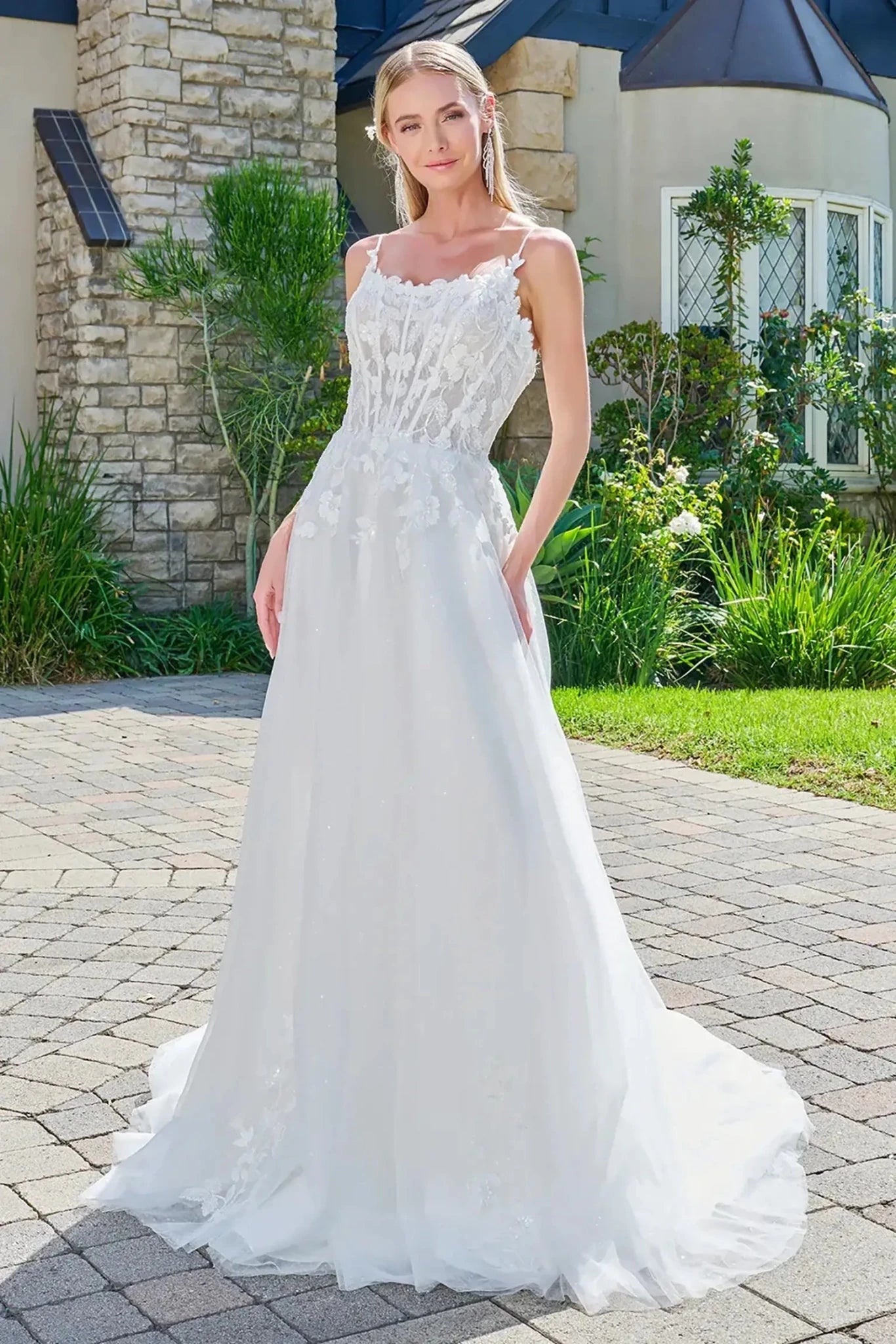 Woman in a white wedding dress standing outdoors on a stone path.