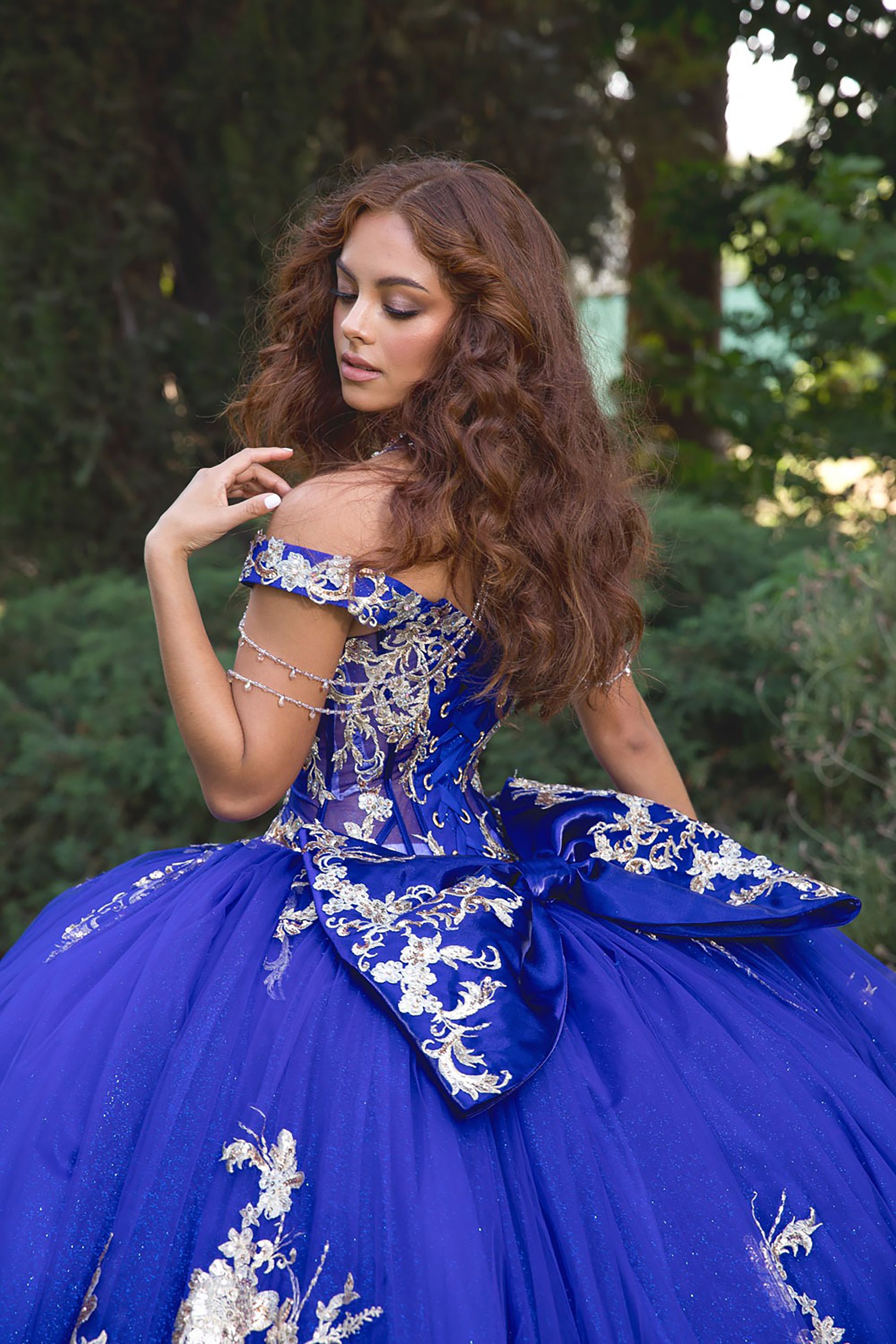 Woman in a blue and gold dress with floral embroidery outdoors.