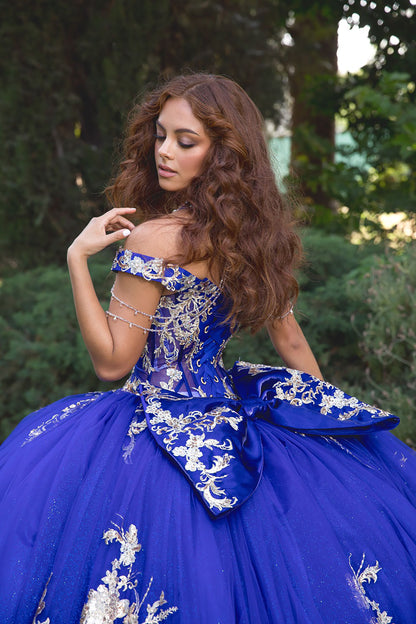 Woman in a blue and gold dress with floral embroidery outdoors.