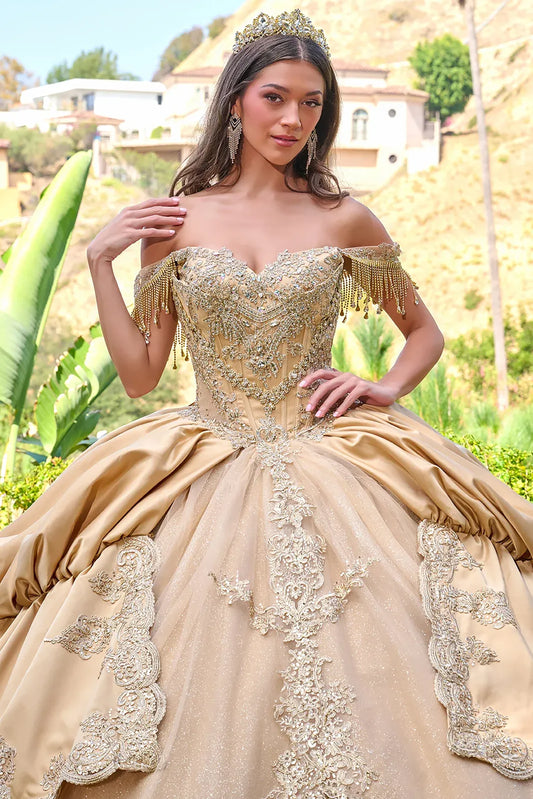 Woman in a beige and gold quince ball gown with intricate detailing outdoors.