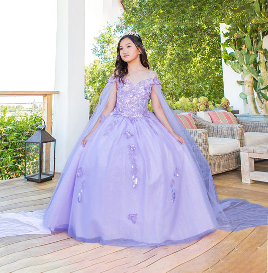 Young girl in a purple gown standing on a wooden deck with greenery in the background