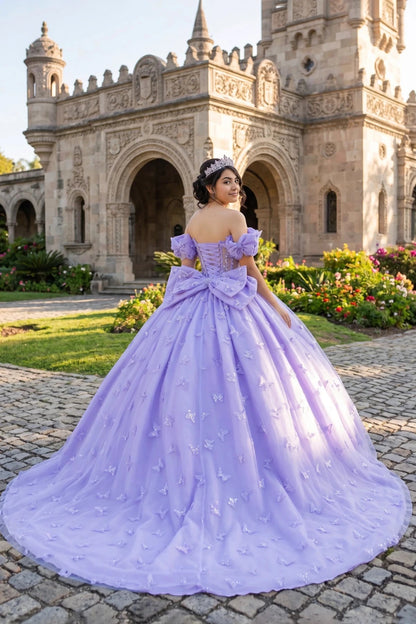 Woman in a lilac quinceanera ball gown with 3D butterflies and  big back bow standing in front of an ornate building with floral gardens.
