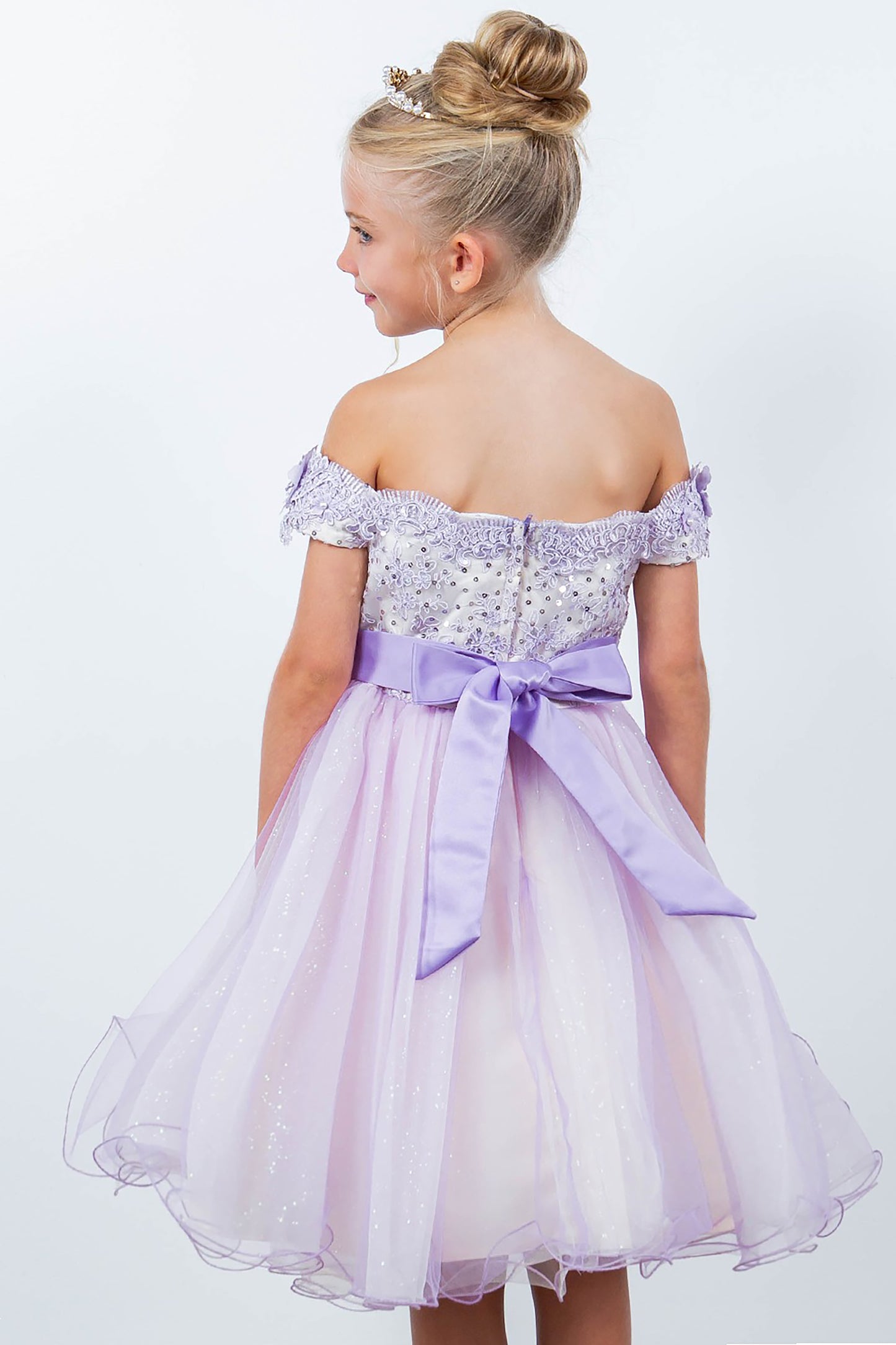 Young girl wearing a lilac off-shoulder dress with a bow on a white background