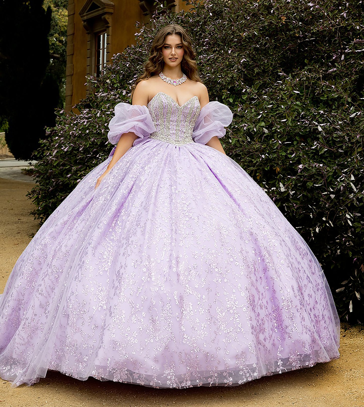 Woman in a lavender gown with puffed sleeves standing outdoors.