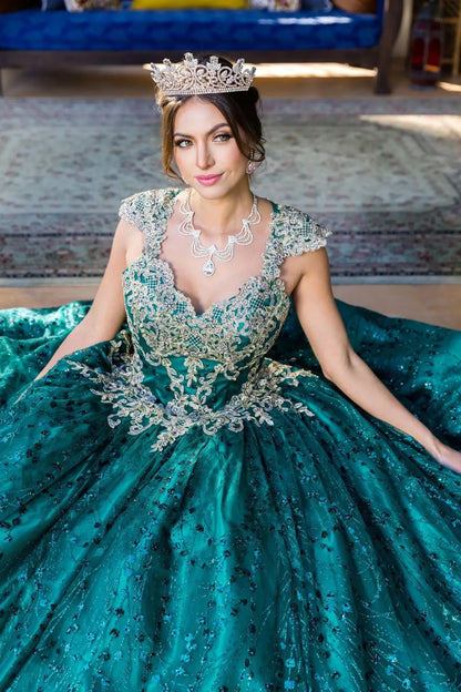 Woman in a hunter green ball gown with intricate detailing and a tiara, sitting on a couch.