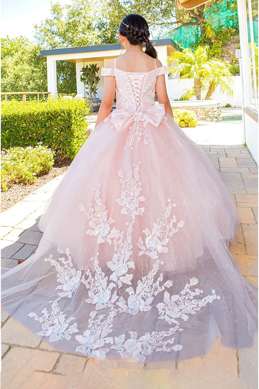 Pink ball gown with long train floral lace details and big bow worn by a kid outdoors.