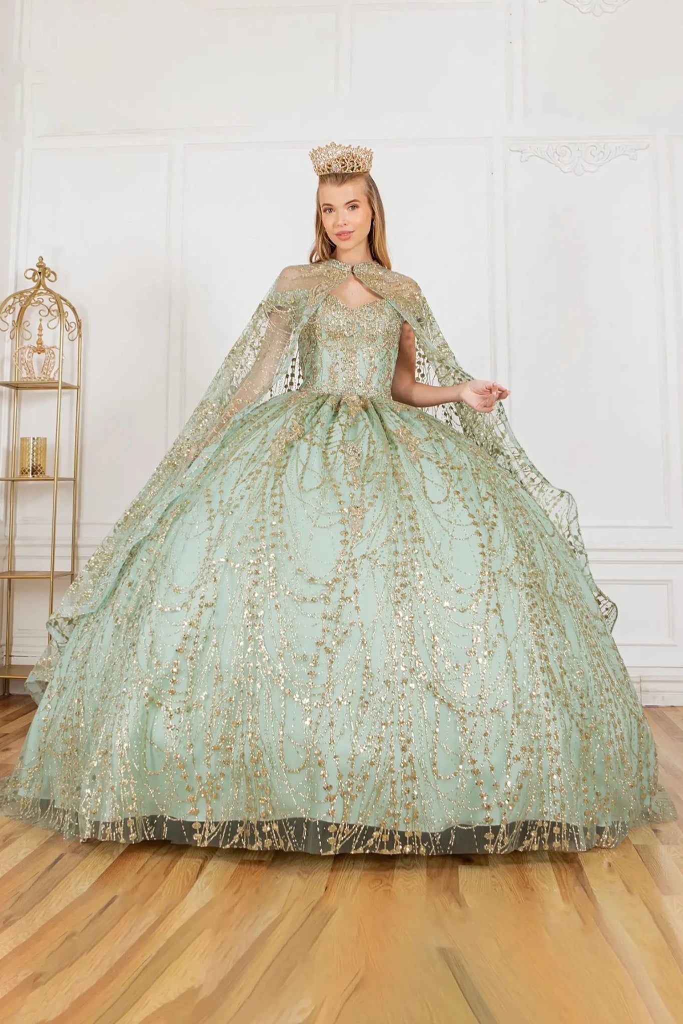 Woman in a sage and gold formal gown with a cape indoors.