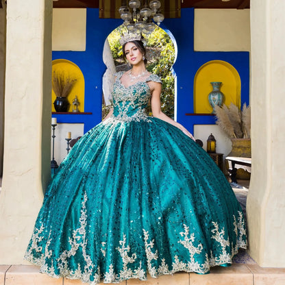 Woman in a teal and silver quinceañera dress standing in a decorated room.