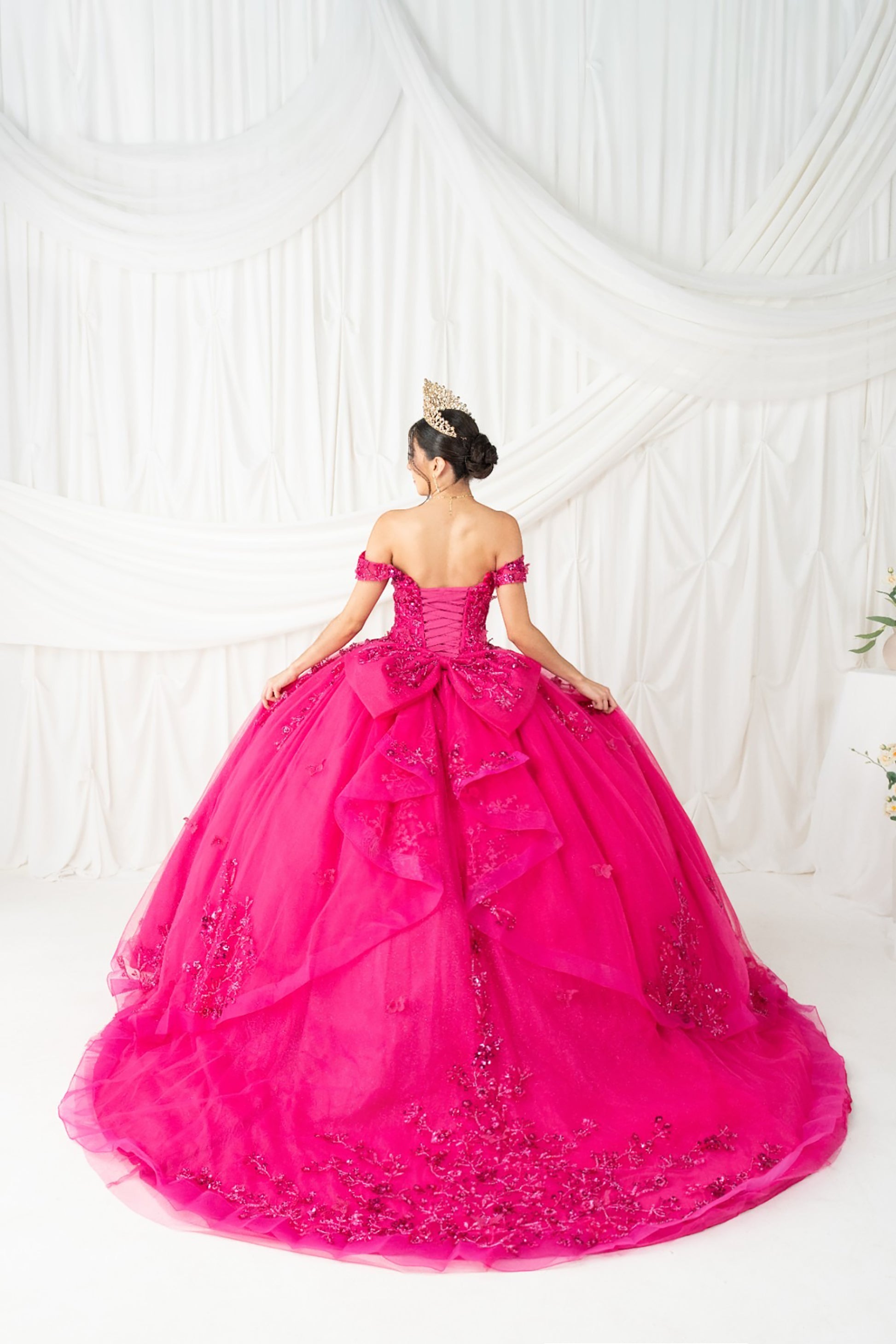  fuchsia ball gown with intricate details on a white background