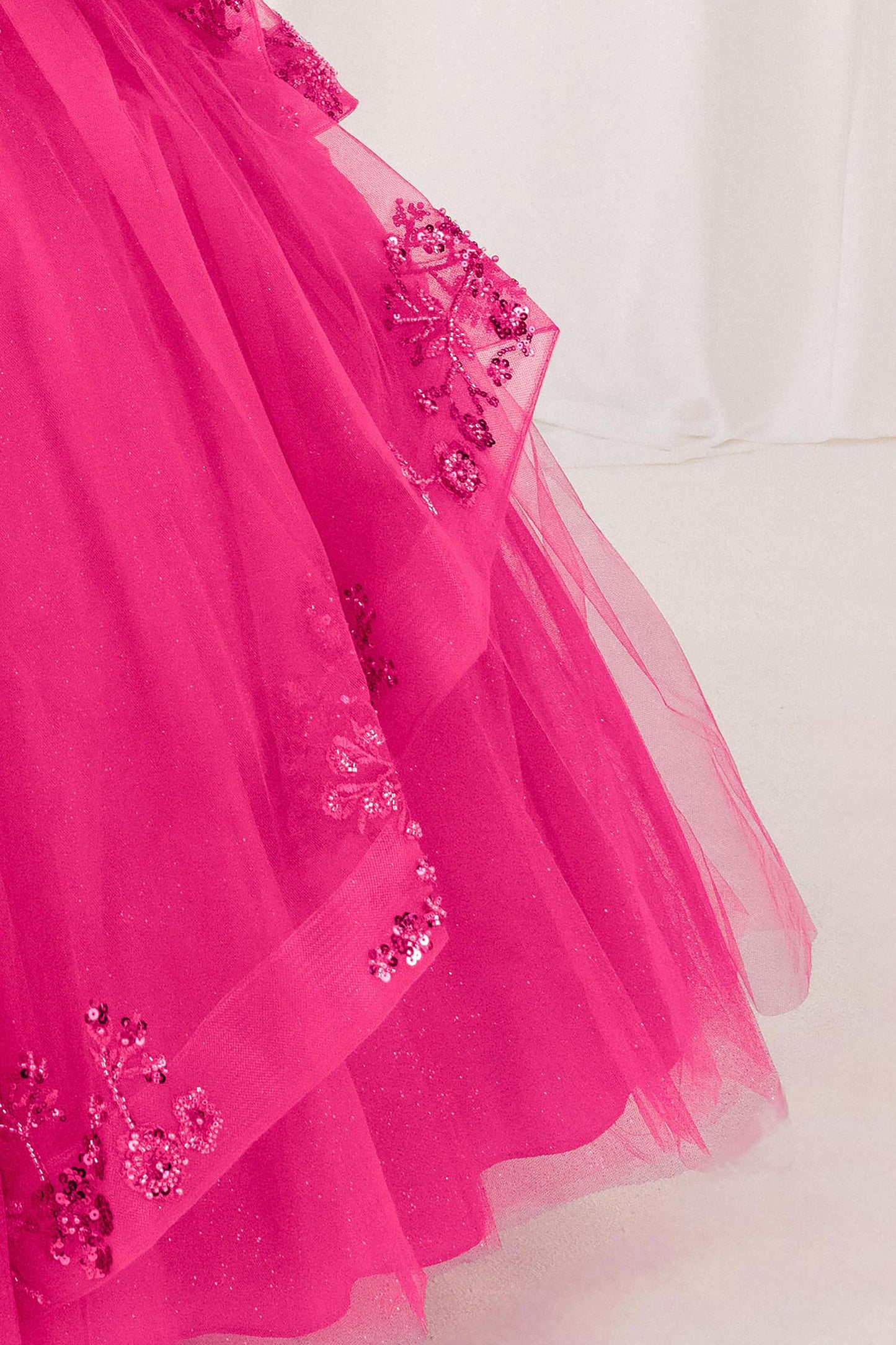 part of fuchsia dress with floral embellishments on a white background