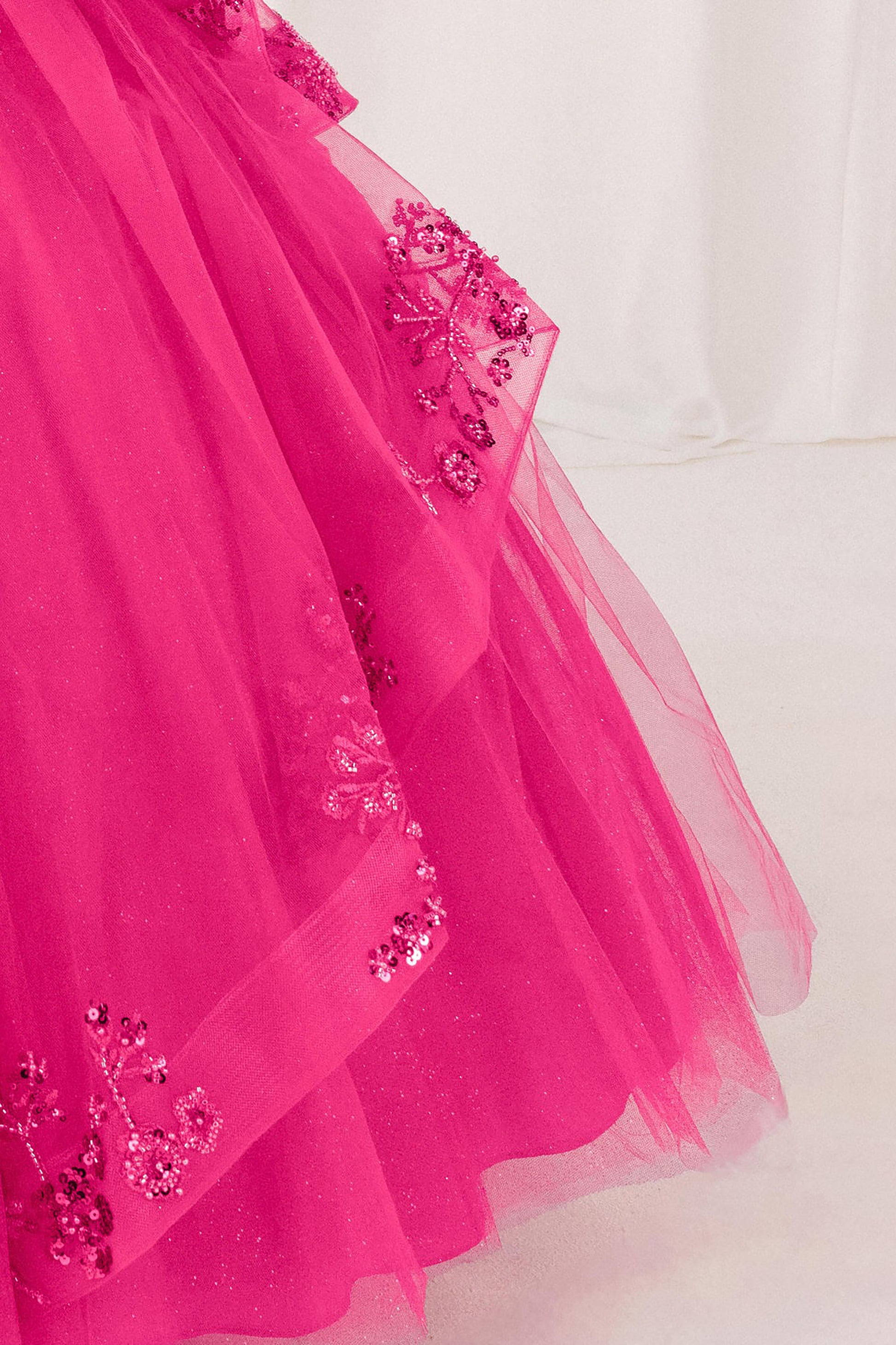 part of fuchsia dress with floral embellishments on a white background