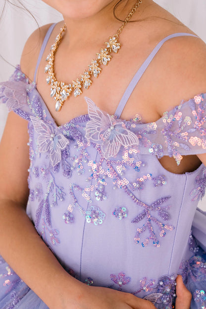 Close-up of a kid wearing a lilac dress with butterfly details and a gold necklace.