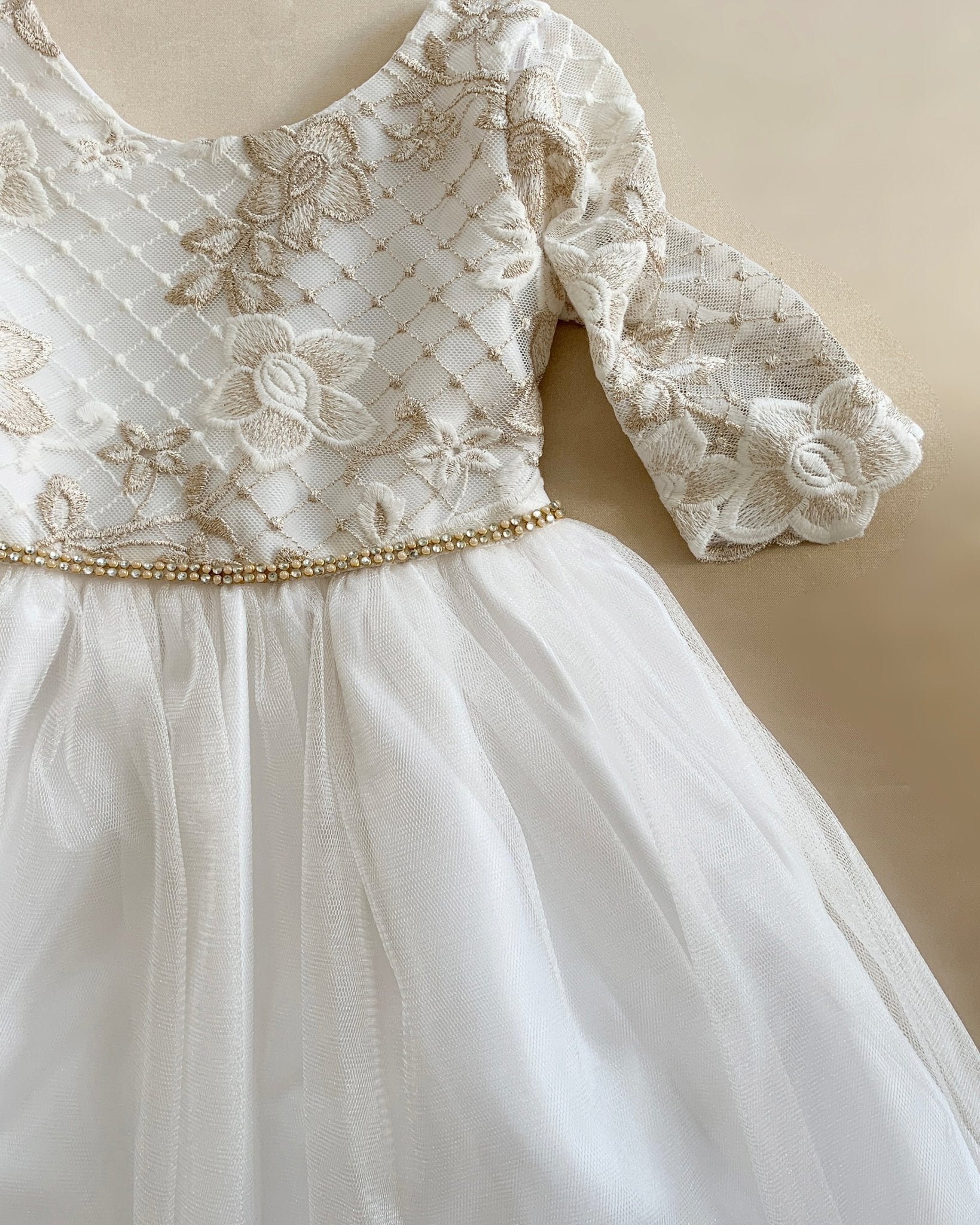 Off-White lace dress with gold embroidery on a beige background