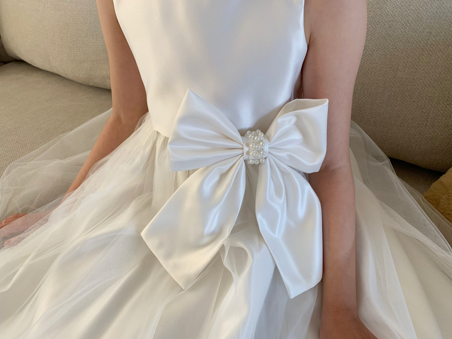 Ivory USA Made | Pearl Neckline & Pearl detail Bow Satin and Tulle Flower Girl Dress - front view of girl wearing dress zoomed in on bow