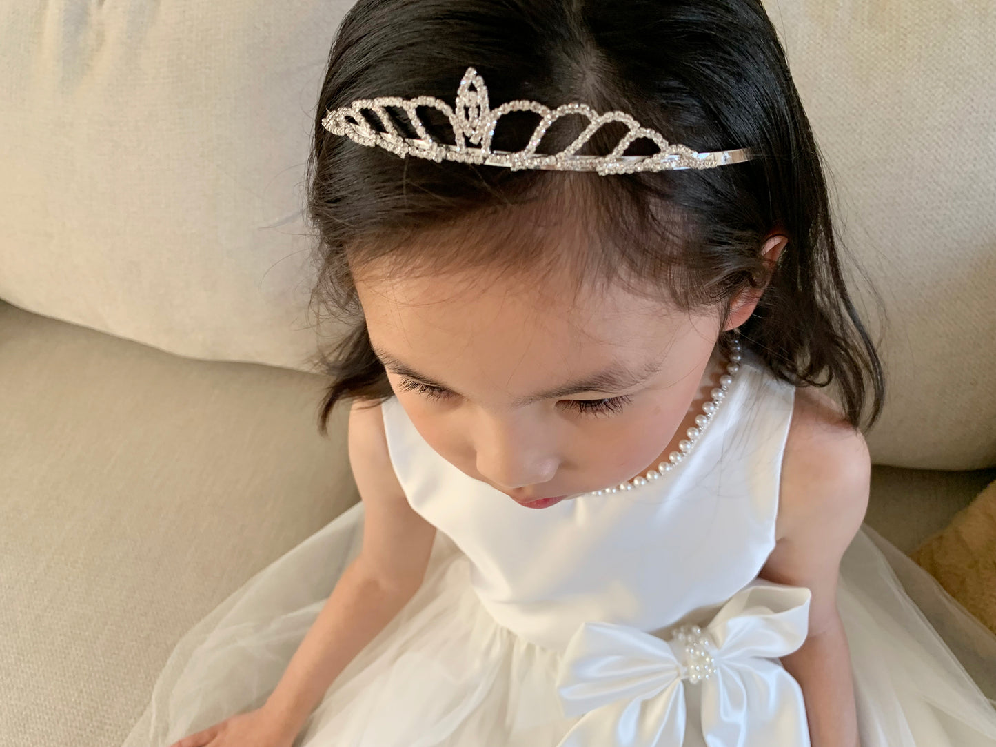 Ivory USA Made | Pearl Neckline & Pearl detail Bow Satin and Tulle Flower Girl Dress - front view of girl wearing dress and crown on head