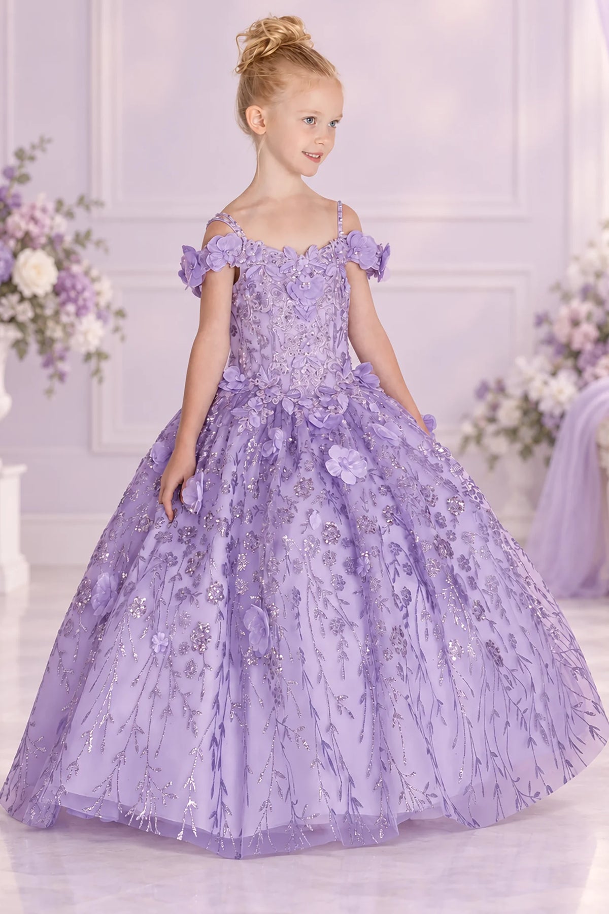 Floral appliqués cover the Lilac mini quinceañera gown, flowing from its fitted bodice onto the glitter tulle skirt.
