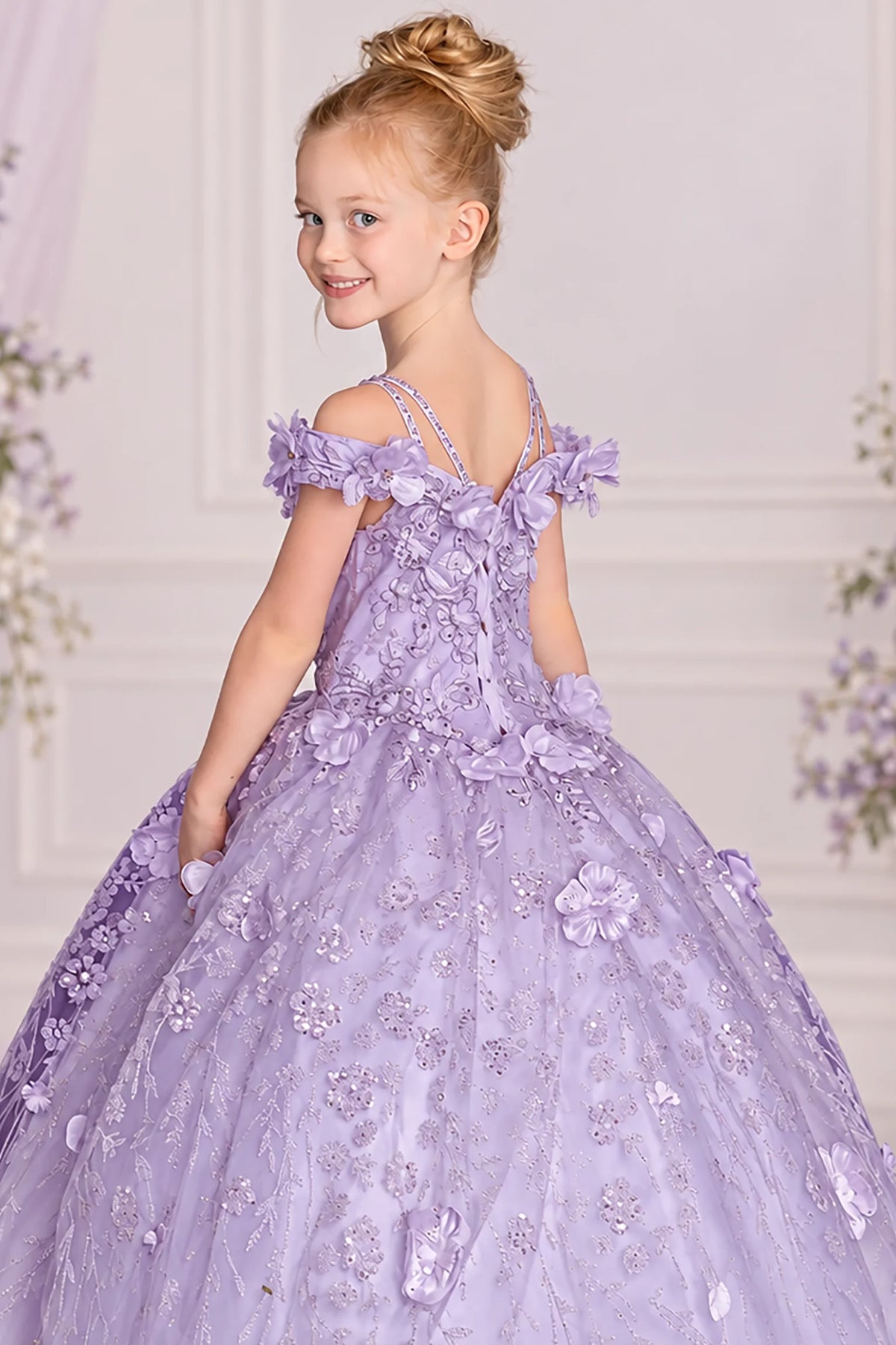 Embroidered vines and off-shoulder floral straps accent the Lilac mini quinceañera gown in this angled view.