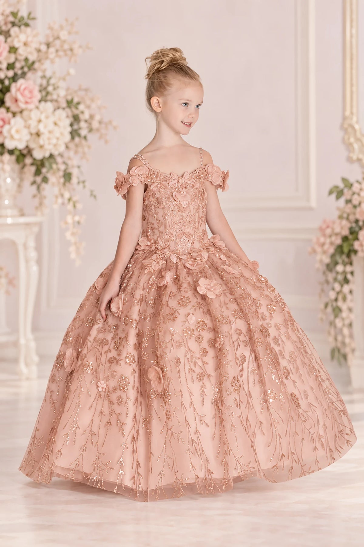 Floral appliqués cover the Rose Gold mini quinceañera gown, flowing from its fitted bodice onto the glitter tulle skirt.