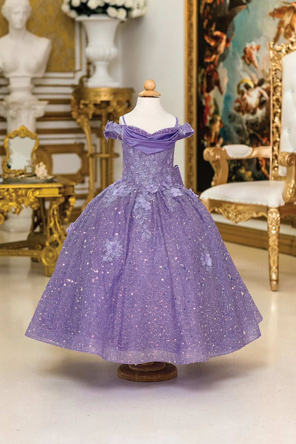 From the neckline, the Lilac mini quinceañera dress shows draped shoulder bands above an allover glitter skirt.