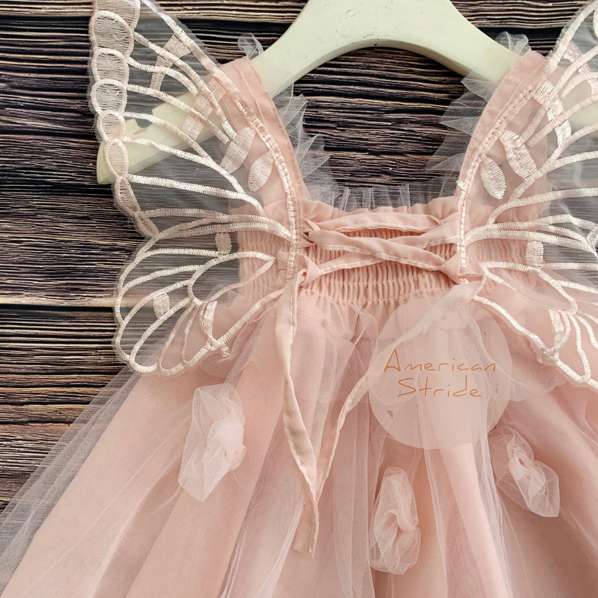 Intricate features stand out across Blush fairy flower girl dress with butterfly wings.
