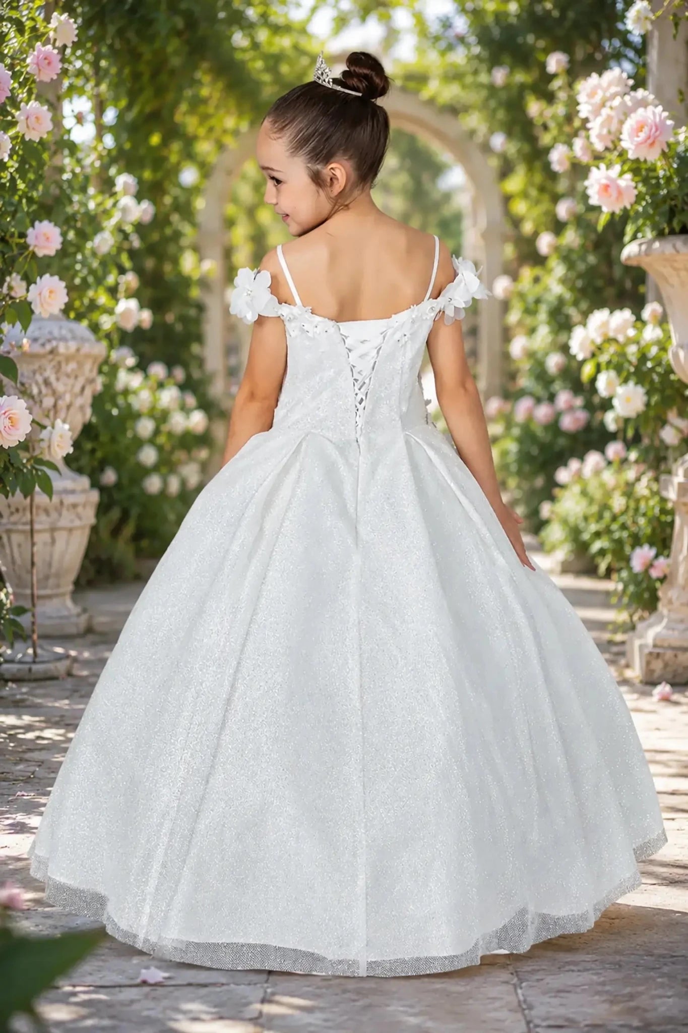 White kids mini quinceañera mini quince dress with lace-up bodice, floral shoulder appliqués, and glitter tulle skirt.