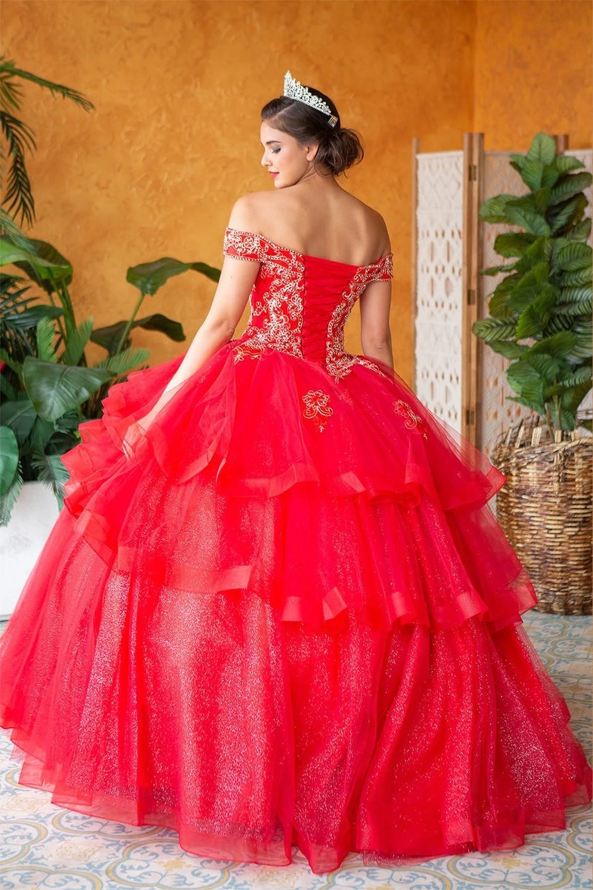 Corset lacing finishes the back of the Red quinceañera ball gown above its layered ruffle skirt.