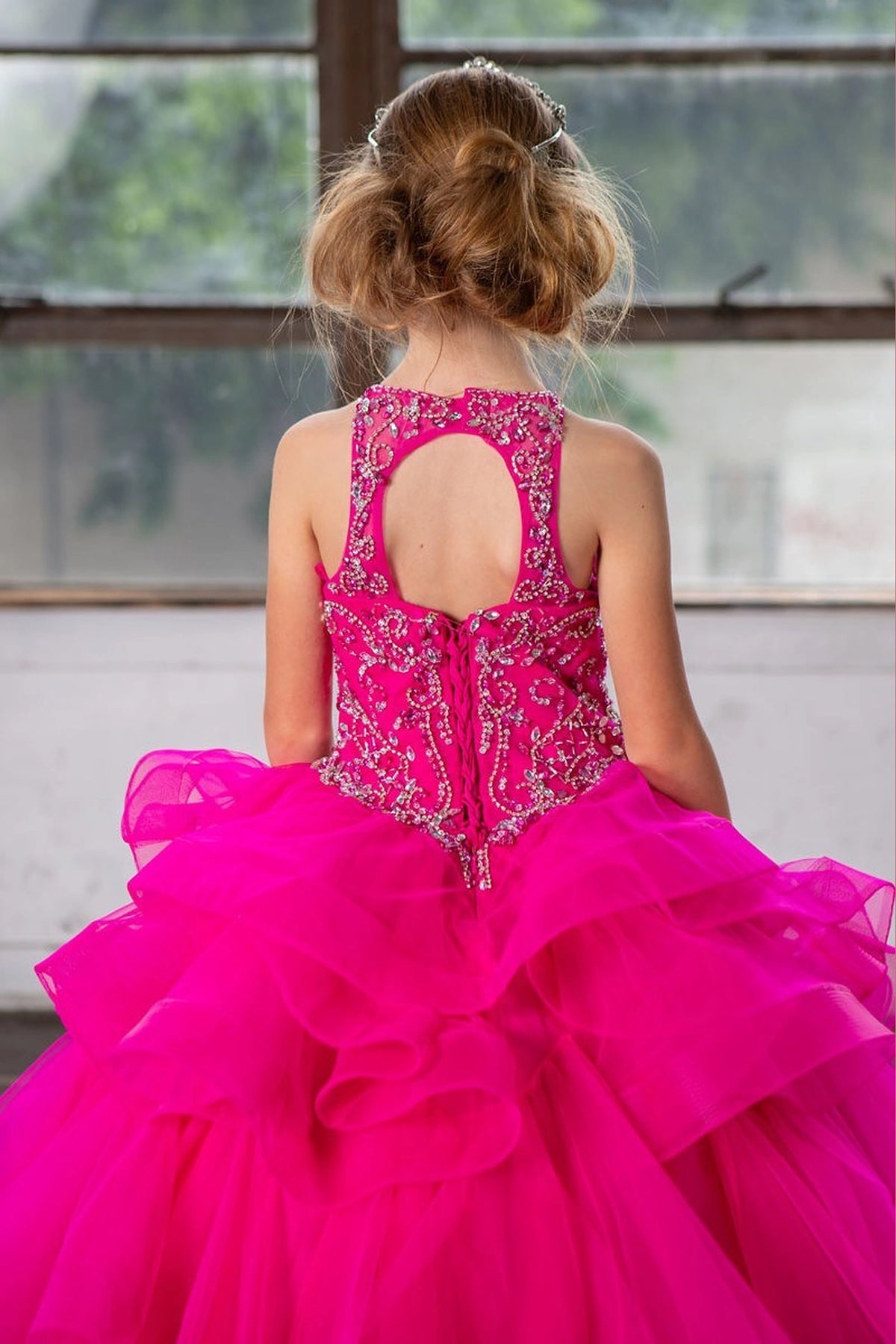 Behind the full skirt, the Magenta mini quince dress displays its lace-up finish and dimensional tiered ruffle skirt.