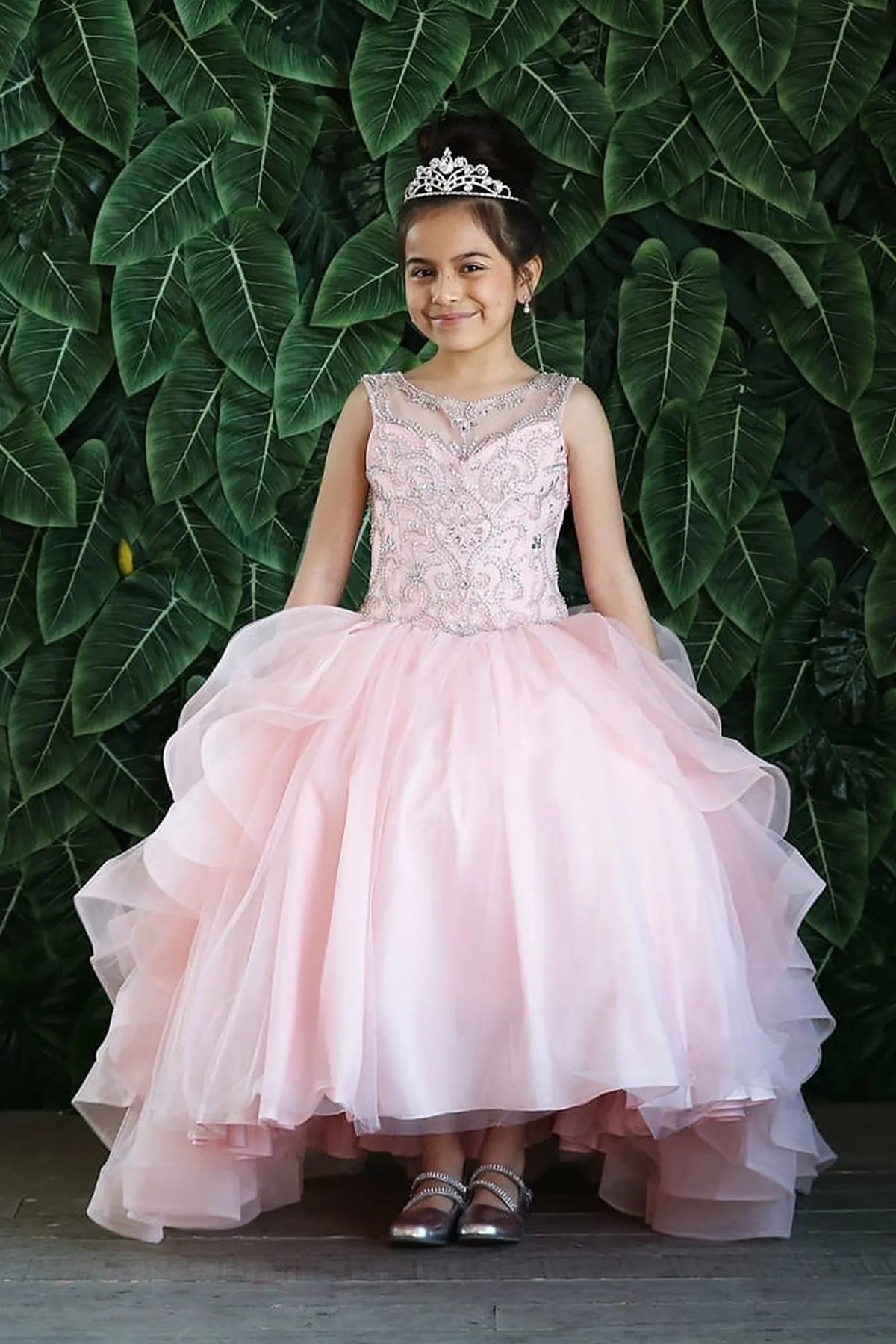 The formal silhouette presents, the Blush Pink mini quince dress showcases crystal-embellished sleeveless bodice and cascading layered ruffle skirt.