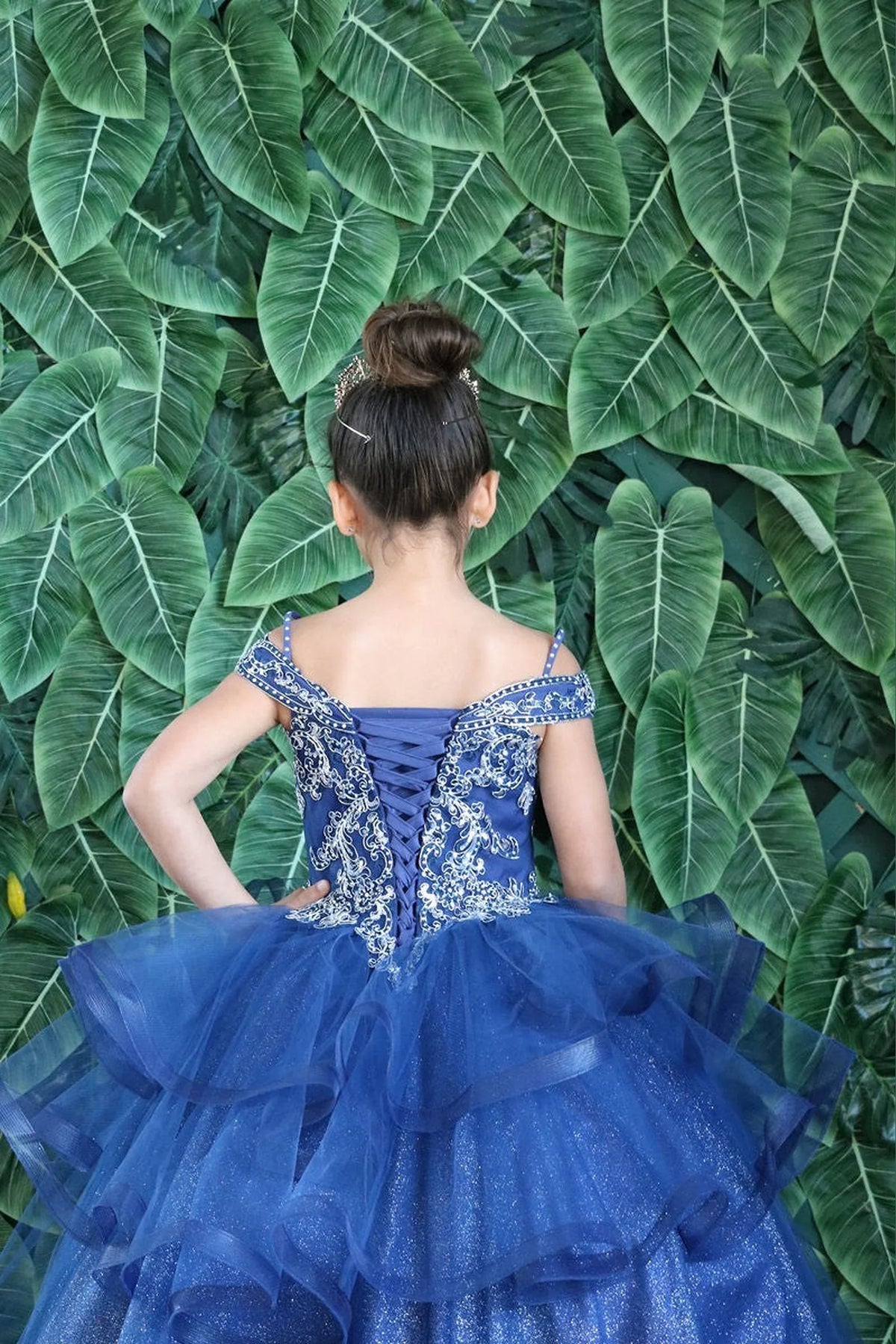 Along the back, the Navy mini quince dress displays its lace-up finish and layered formal skirt with dimensional tiers.