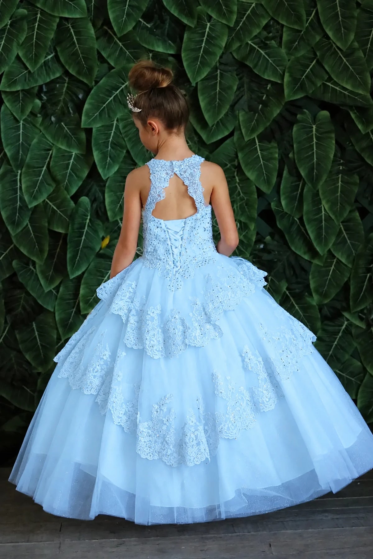 Turning to the back, the Bahama Blue mini quince dress displays its lace-up finish and full layered tulle skirt with ruffle tiers.